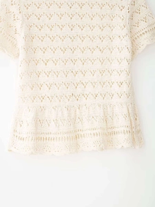 Detail of beige crochet knit top showing intricate hollow patterns and wavy textures
