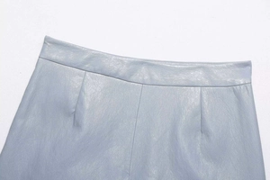 Détail de la taille irrégulière et texture du cuir PU sur la jupe bleu clair