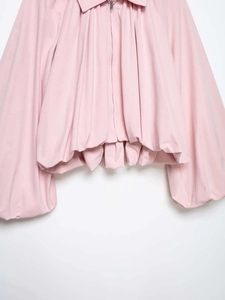 Detailed view of pink puff sleeve jacket with zip-up front and gathered elastic hemline