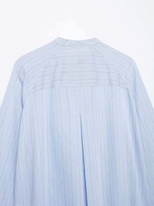Detail of light blue pinstripe fabric with band collar and modern stitching
