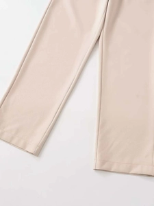 Détail de la double couture de qualité sur l'ourlet du pantalon beige et tissu lisse
