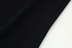 Close-up of black chiffon fabric texture with precise hem stitching on wide-leg trousers