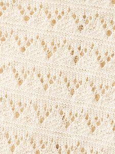 Macro detail of cream knit fabric featuring geometric hollow diamond crochet patterns