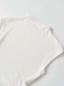 Close-up of white ribbed knit fabric detailing the high neckline and sleeveless shoulder