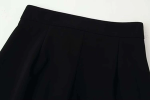 Macro detail of high-quality black pleated waist design and stitching on wide-leg trousers