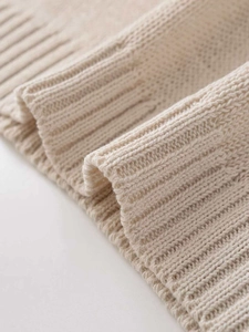 Macro view of beige ribbed knit cuffs showcasing high-quality soft wool texture