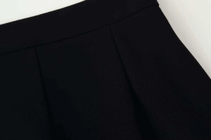 Detail view of the high-waist black wide-leg trousers showing pleated design and texture