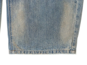 Detailed close-up of light blue denim hem with professional stitching and distressed texture