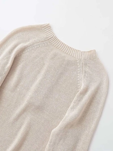 Detailed view of apricot knitted sweater showing raglan sleeve design and fine texture