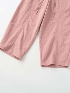Close-up of rose pink breathable pants featuring drawstring waist with gold metal tips