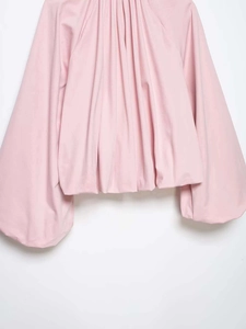 Detail of light pink lantern sleeve blouse showing pleated neckline and fabric texture