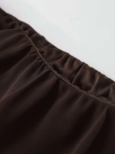 Macro detail of elastic waistband with gathered stitching on dark brown midi skirt