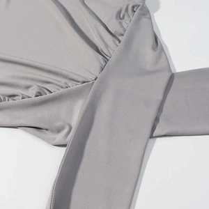 Detail of grey sleeveless top featuring crossover pleats and elastic knit fabric texture