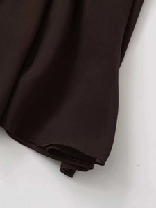 Detail shot of a dark brown midi skirt showing micro-textured fabric and fine rolled hem