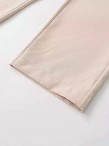 Détail du pantalon beige montrant les coutures de l'ourlet et la texture du sergé