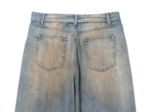 Detail view of vintage light blue denim jeans with distressed wash and back pockets