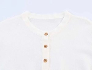 Detail of white knit top neckline featuring three brown marble textured buttons