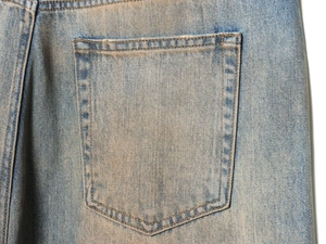 Detail of light blue denim jeans rear pocket with double stitching and distressed edges