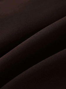 Macro detail of dark brown crepe fabric showing soft texture and fine grain finish