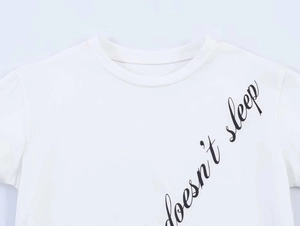 Detail of the white crew neck T-shirt with black 'doesn't sleep' italic print on the chest