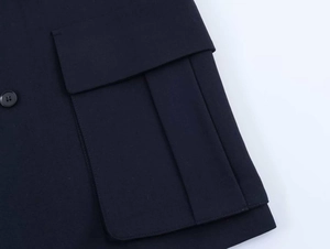 Detail view of the navy blue blazer featuring a cargo pocket with pleated design