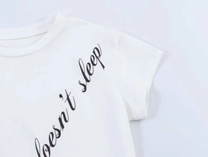 Close-up of white cotton T-shirt neckline with black handwritten doesn't sleep print