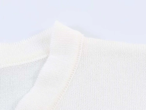 Close-up of a white slim fit knit sweater showing detailed round neckline texture