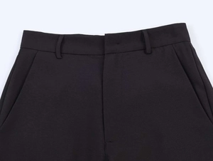 Detail of high-waist black wide-leg trousers featuring side pockets and a clean waistline