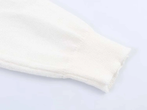 Detailed macro view showing the fine rib-knit cuff texture of the white knitted sweater