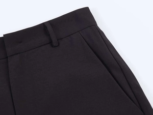 Detailed close-up of waistband with belt loops and side pockets on black trousers