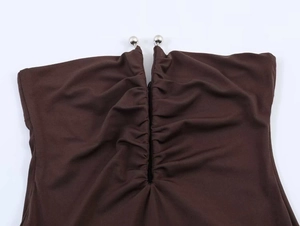 Detail of chocolate brown knit dress with pleated neckline and silver sphere accents