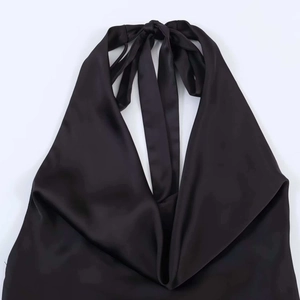 Detail of black satin halter dress showing deep V-neckline and smooth silk texture