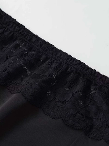 Close-up detail of high-quality black knit fabric with elegant floral lace trim edging