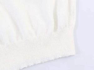 Close-up of the fine knit texture and ribbed hem on a white slim fit knit sweater