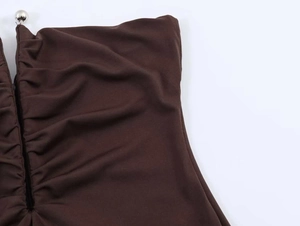 Detail of dark brown ruched tube dress with a silver metallic ball decoration at neckline