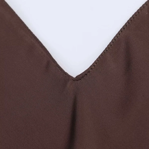 Détail en gros plan du col en V sur une robe en satin marron chocolat et coutures