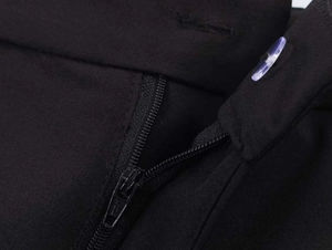 Close-up of black commuter suit trousers showing zipper fly detail and translucent button