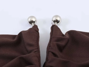 Detail shot of a dark brown strapless dress showing silver metallic ball accents on ties