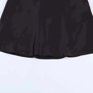 Macro detail of glossy black satin fabric hem showing silky texture and smooth drape