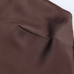 Gros plan détaillé montrant les coutures précises et la texture satinée marron du vêtement