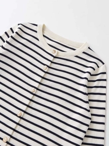 Close-up of cream knit cardigan with navy stripes and textured gold buttons