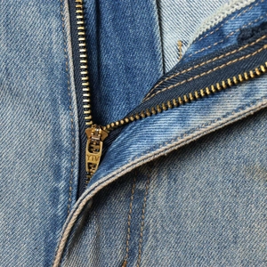 Close-up of classic blue denim jeans with yellow stitching and metal zipper fly detail