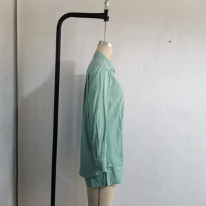 Side view of striped green shirt featuring curved hem and side slit on mannequin