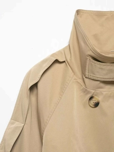 Detailed close-up of khaki trench coat collar with amber buttons and epaulette stitching