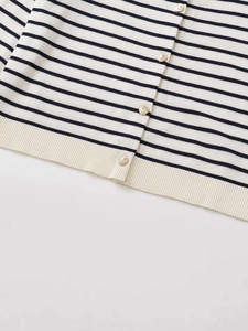 Close-up of knit cardigan with black and white stripes and embossed gold buttons