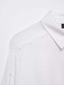 Close-up of white cotton linen shirt showing intricate lace stitching and fabric texture