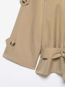 Detail of khaki trench coat featuring buttoned epaulettes and textured twill fabric
