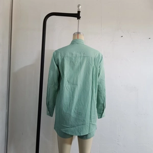 Close-up of green and white striped long sleeve shirt with box pleat back and curved hem