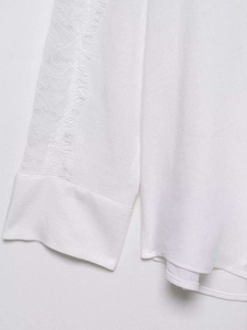 Close-up of white linen cotton shirt with delicate lace stitching and folded cuffs