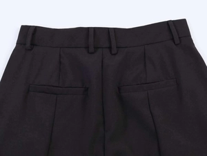 Detailed view of rear welt pockets and belt loops on black wide-leg suit trousers